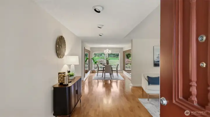 A welcoming entry opens to beautiful engineered hardwood floors and a light-filled dining area framed by expansive windows and serene outdoor views.