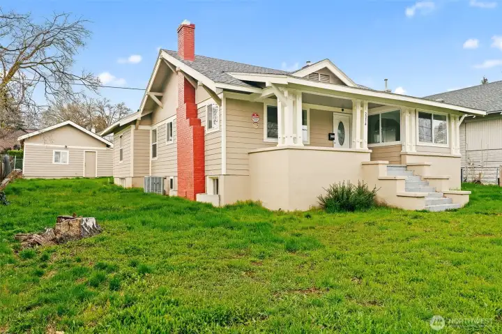 Yard and home side view featuring covered front porch and detached garage