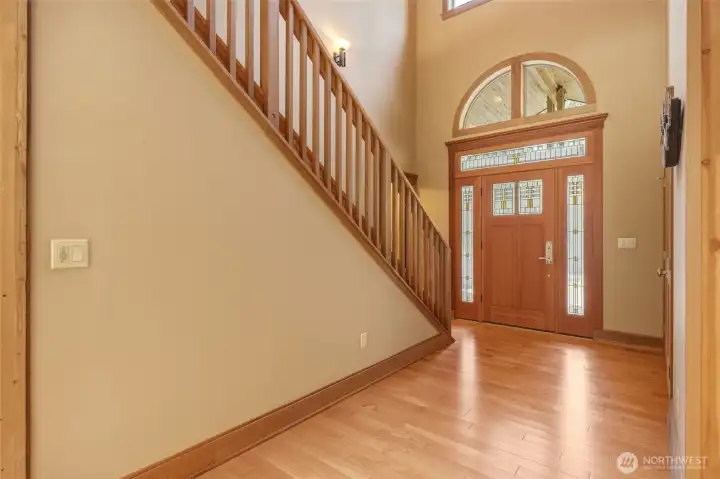 Stained and leaded glass doorway with arched windows in this 20 ft foyer bring in natural light and set the tone upon entry.