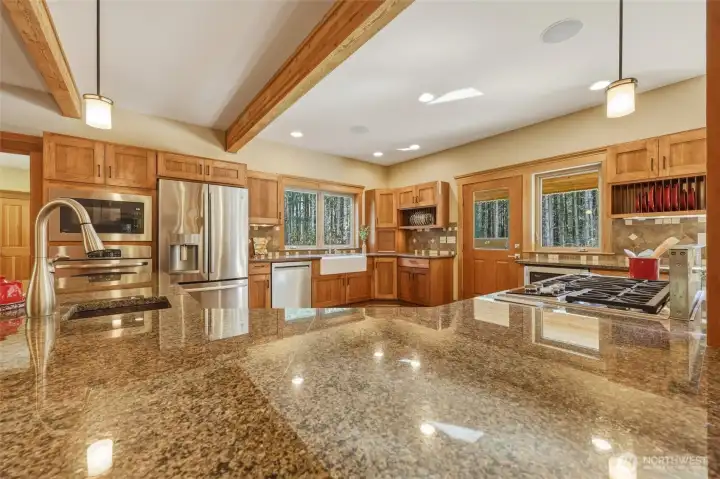 Slab granite island with hammered copper prep sink and pendant lighting provide bountiful workspace.