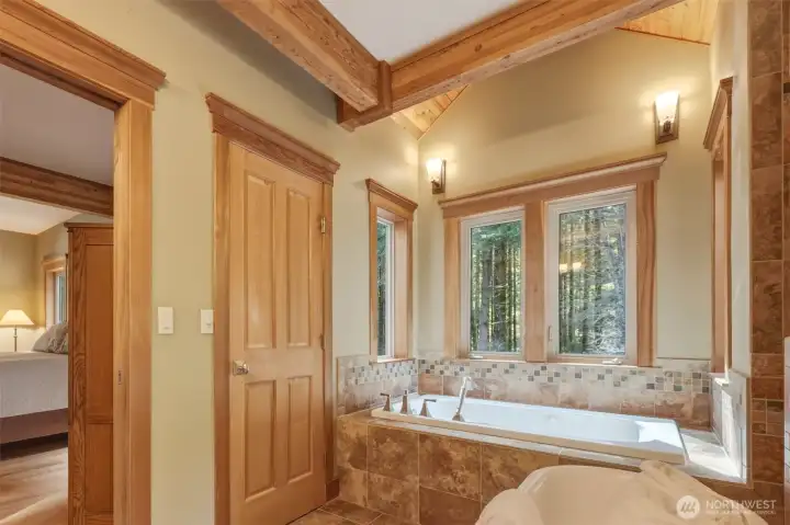 Spa-inspired primary bath; Let it all go in your jetted tub beneath exposed beams and vaulted cedar ceiling, surrounded by views of nature! Linen closet keeps everything handy.