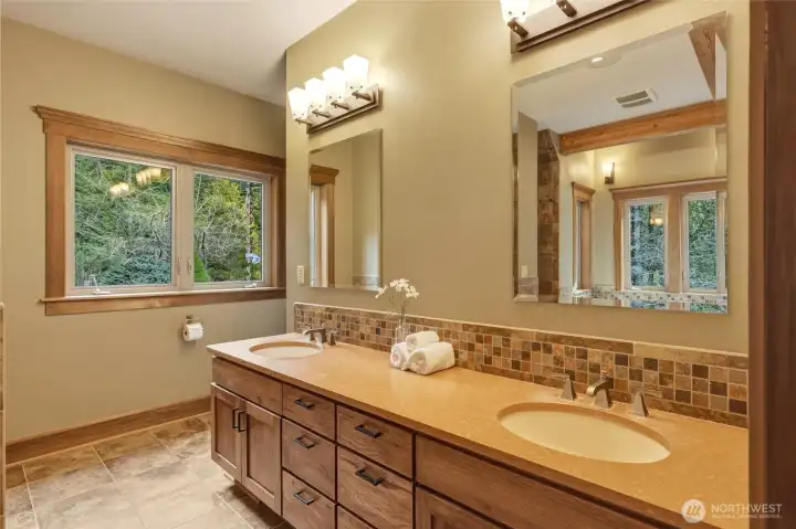 Dual sinks in smooth, natural stone counters, multiple drawers for storage, and gorgeously-wrapped windows for so much natural light.