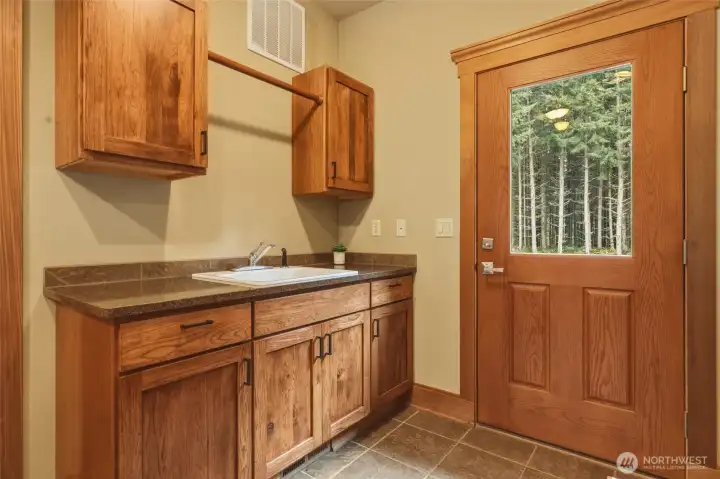 On the other side of the home, adjacent to the garage, is this convenient mudroom with utility sink, storage, hanging bar, and exterior door for those quick in-and-outs!