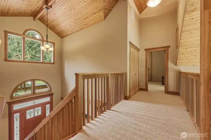 Climbing the staircase is a heavenly ascent with all of the gorgeous wood, beautiful windows, and vaulted ceilings! Linen closet shown here, and door to 2nd primary.
