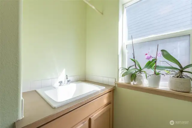 The laundry sink has its own cabinet tucked into a private area.