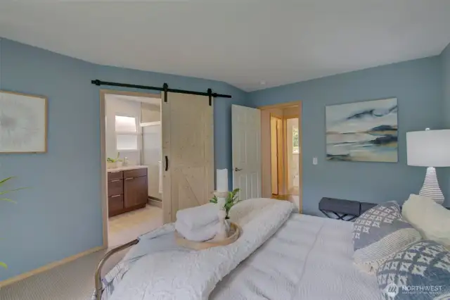 Enter the attached primary bathroom through the custom barn door.