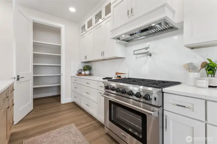 This exceptional kitchen combines beauty and functionality with high-end THOR appliances, including a professional-style gas range and oven with a convenient pot filler and matching THOR microwave. The soft-close cabinetry is thoughtfully designed with smart storage solutions and custom extras that make daily living effortless. A spacious walk-in pantry keeps essentials neatly tucked away, ensuring your kitchen stays organized, uncluttered, and ready for both everyday meals and grand entertaining.
