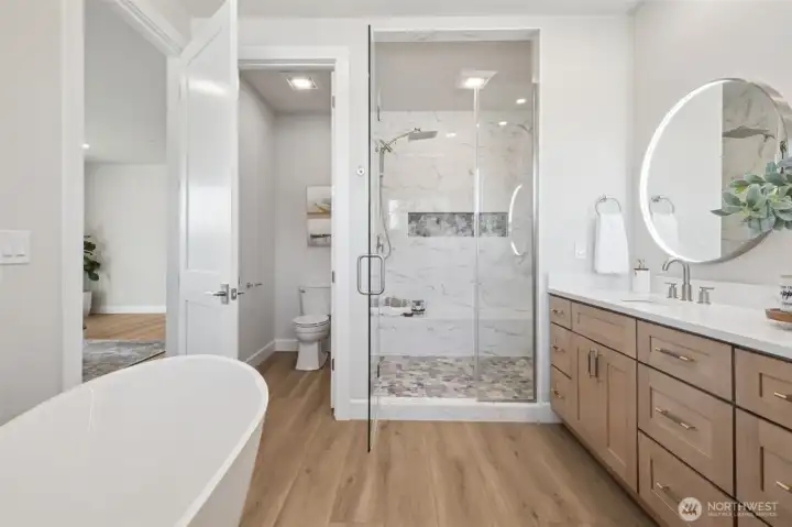 Escape into a luxurious bath featuring a freestanding soaking tub, a walk-in shower with dual shower heads and bench, and a dual sink vanity. Every element has been chosen to elevate your daily routine into a moment of indulgence.