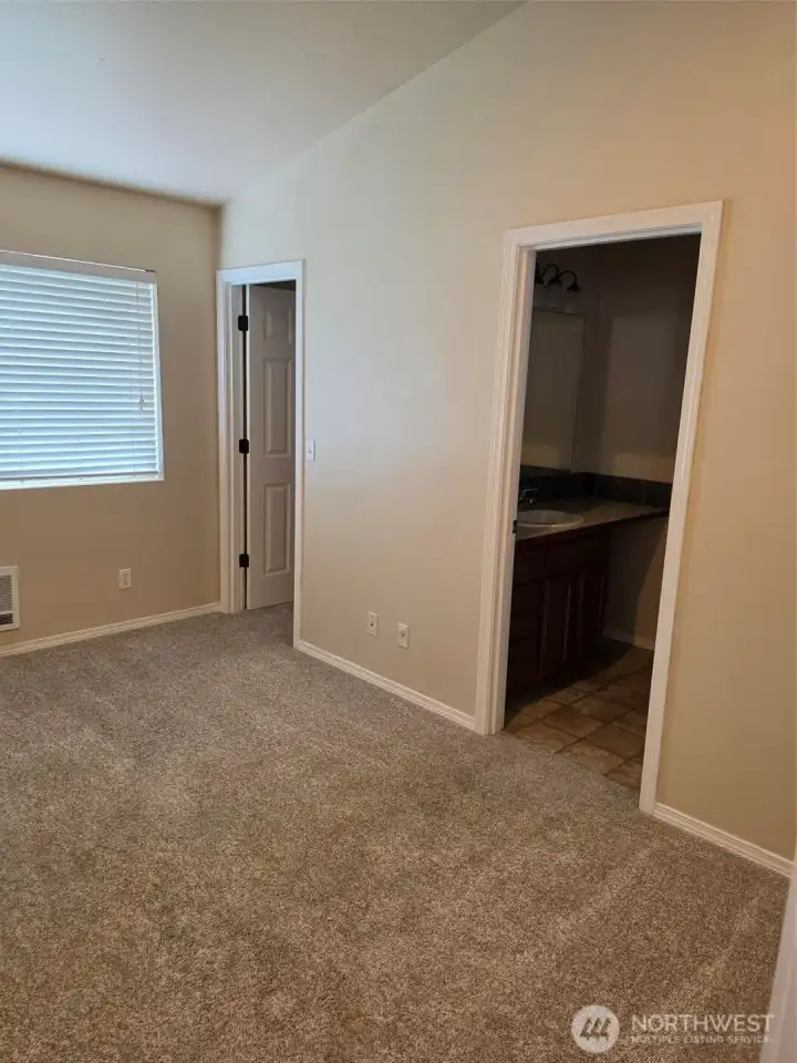 Primary Bedroom Suite with Walk in Closet by window and open door to bathroom Primary Bedroom Suite with Walk in Closet by window and open door to bathroom