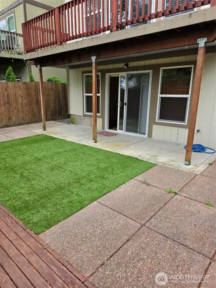 Back yard patio and slider to family room with main floor deck above. Upper deck has metal underneath to direct rain away from the patio. Note the minimal grass Back yard patio and slider to family room with main floor deck above. Upper deck has metal underneath to direct rain away from the patio. Note the minimal grass