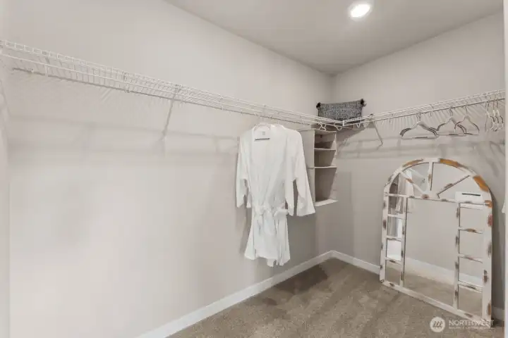 Large walk-in closet for primary suite. Photo rendering is representational and may be virtually staged. Actual home is under construction and finishes, elevation, and paint colors may vary. See site agent for details. Large walk-in closet for primary suite. Photo rendering is representational and may be virtually staged. Actual home is under construction and finishes, elevation, and paint colors may vary. See site agent for details.