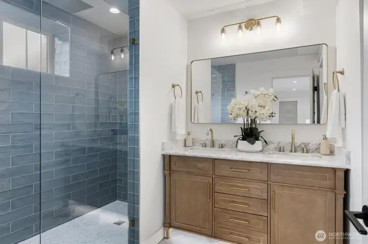 Primary Bathroom complete with large walk in shower, dual sink vanities, a separate water closet, and artisan tiling