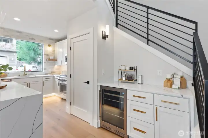 Tucked beneath the staircase, this sleek countertop zone—with its built-in wine cooler and curated coffee setup—adds a touch of luxury and convenience to the kitchen’s clean-lined elegance.