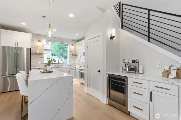 The large kitchen window floods the space with natural light, framing outdoor greenery while enhancing the airy, open feel of the room’s modern design.