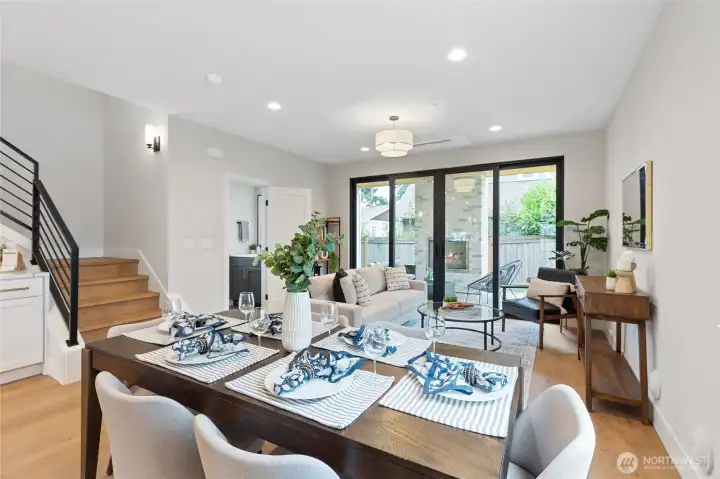 This open concept living and dining area flows effortlessly, creating a welcoming space for entertaining or relaxing. Natural light pours in through expansive glass doors, connecting the indoors to the lush patio and enhancing the home's warm, modern vibe.