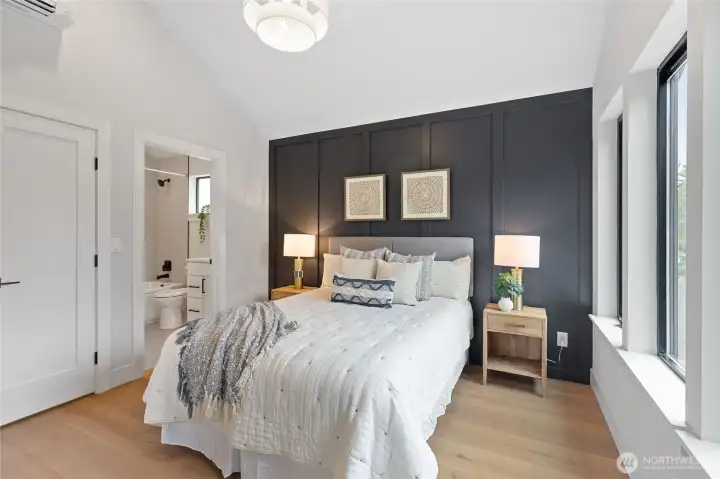 This bedroom offers a clean, modern retreat with soft textures, a dark accent wall, and vaulted ceilings—bathed in natural light for a bright, welcoming feel.
