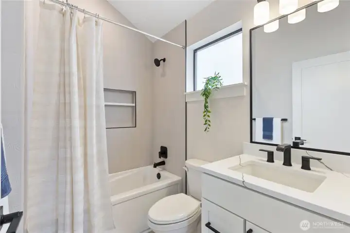 This modern bathroom pairs clean lines with bold black fixtures, offering a fresh, functional space accented by soft neutrals.