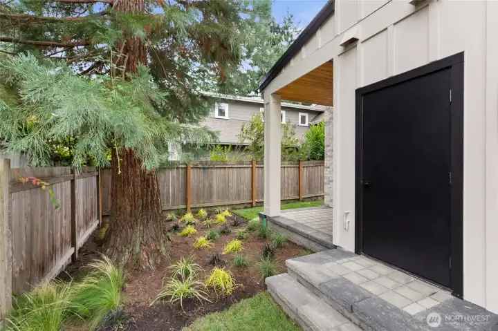 Landscaped side yard with neat mulch beds, ornamental grasses, and a covered porch—simple, serene, and easy to enjoy.