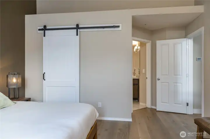 Sophisticated primary suite boasts a space-saving rolling door for the walk-in closet and a private 5-piece en-suite bath