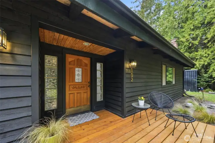 Inviting covered entry features natural wood accents and contemporary dark siding.