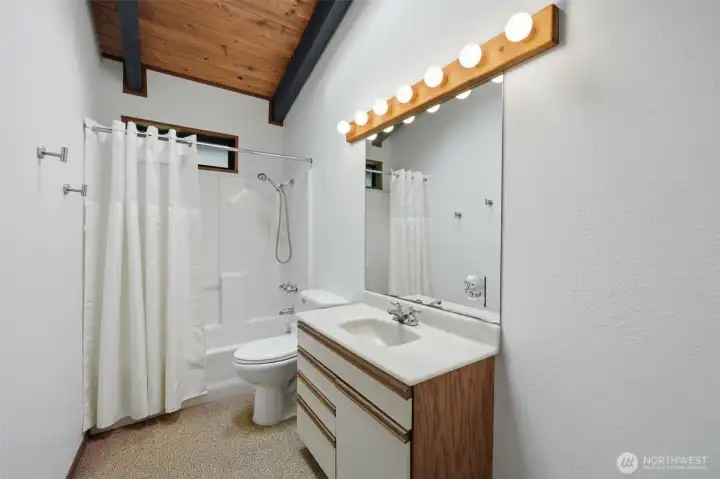 Refreshing full bathroom with clean white finishes and large vanity mirror.