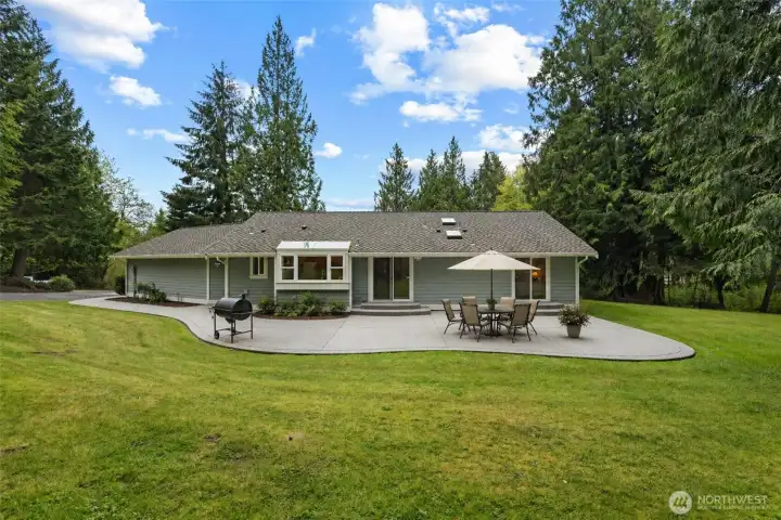 Looking from the woods lining the edge of the property, the enormous patio is perfect for entertaining!