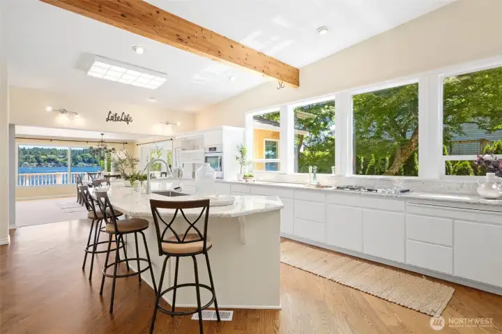 Kitchen features vaulted ceilings, exposed wood beams, and charming hardwood floors.