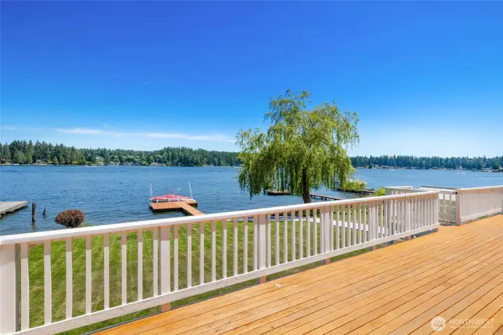 Expansive deck off of main living area with stairs leading to a paved path to the lake.