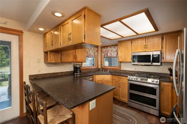 Kitchen has custom oak cabinets with adjustable shelving, granite counters, Samsung dual fuel stove with air-fryer and microwave with exhaust.
