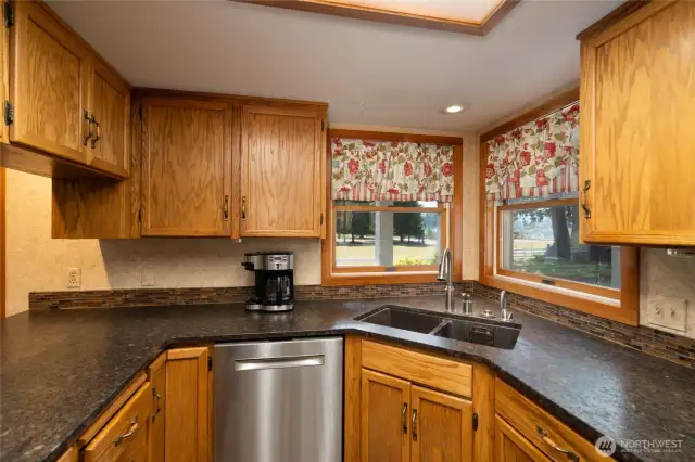 Custom oak kitchen cabinets with Bosch dishwasher. Enjoy the view from the corner windows above sink, with garbage disposal and instant hot water dispenser.