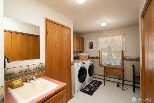 Spacious laundry room is next to back porch entrance with deep sink, 1/4 bath toilet room, custom cabinets with storage for organization and large coat closet or pantry.