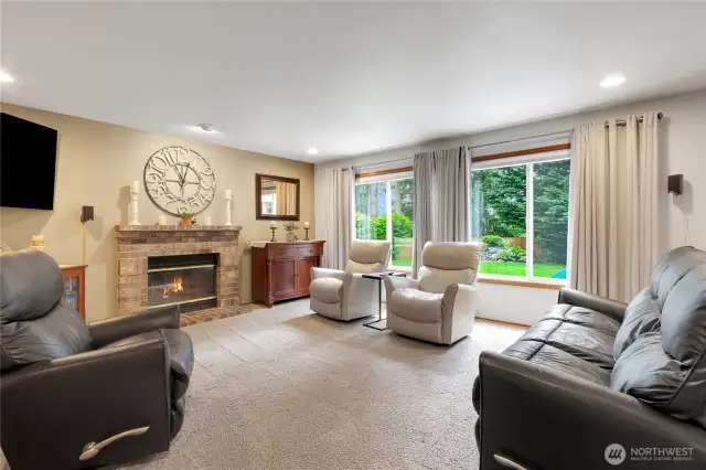 Inviting family room featuring a wood-burning fireplace and large windows that frame picturesque views of the beautiful backyard.