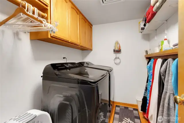 Generously sized laundry room, fully plumbed for a utility sink and equipped with ample cabinetry and shelving for convenient storage and organization.