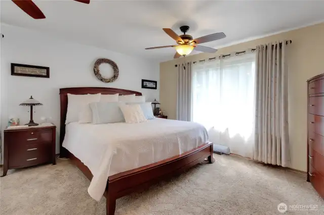 The expansive primary suite features an oversized bedroom with a large window showcasing stunning sunsets and partial mountain views. It includes a private attached bathroom and a spacious walk-in closet, offering both comfort and luxury.