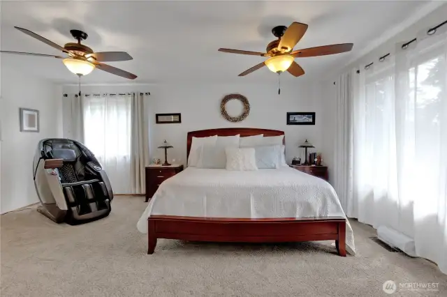 The expansive primary suite features an oversized bedroom with a large window showcasing stunning sunsets and partial mountain views. It includes a private attached bathroom and a spacious walk-in closet, offering both comfort and luxury.