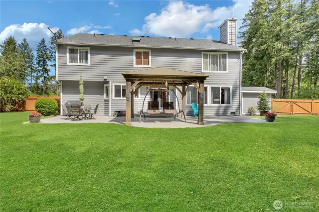 Spacious, fully fenced backyard with double gates, offering mature landscaping, a sprinkler system, and excellent privacy. Highlights include a stamped concrete patio with a gazebo, a tranquil water feature, a garden area, storage shed, big toy play space, and plenty of room for entertaining and outdoor activities.