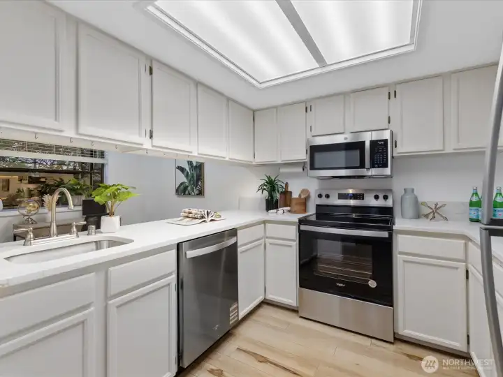 The kitchen is light and pleasant, with a welcome, open feel. It features loads of cabinetry and work space, new quartz counters, sink and stainless appliances.