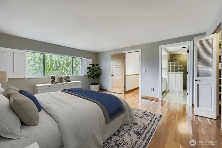 More gleaming hardwoods! The Primary Suite also boasts a wall of windows with plantation shutters and entrance into the adjoining bath.