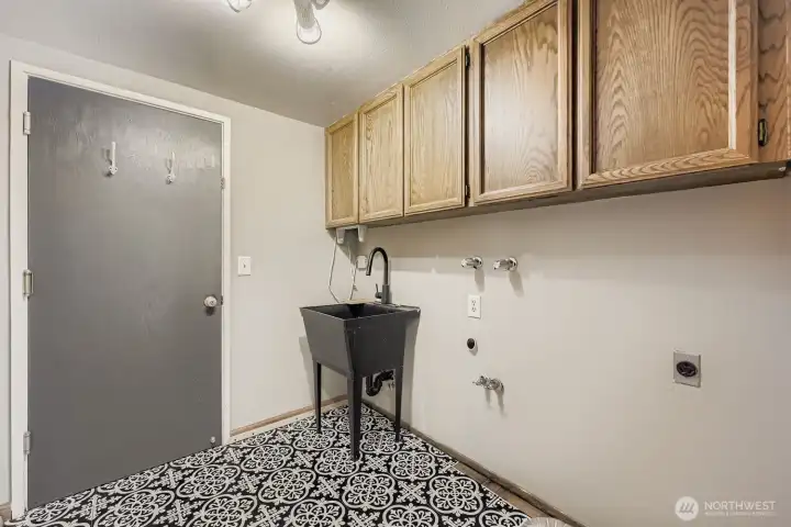 Fun vinyl flooring, extra overhead cabinets and a laundry basin are featured in the utility room, which leads out to the 2-car garage.
