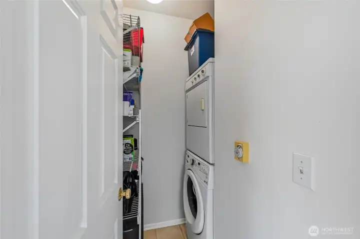 The laundry room is conveniently equipped with a stacked washer and dryer and also provides ample additional storage.