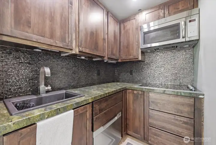 This fancy Kitchenette with Tasteful Marble counters & and Glass backsplash is located in the in the ADU