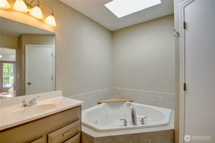 A large soaking jacuzzi tub with a skylight to bring in the light.