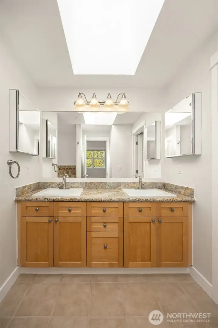 Double sink vanity with granite counters & tile floors.