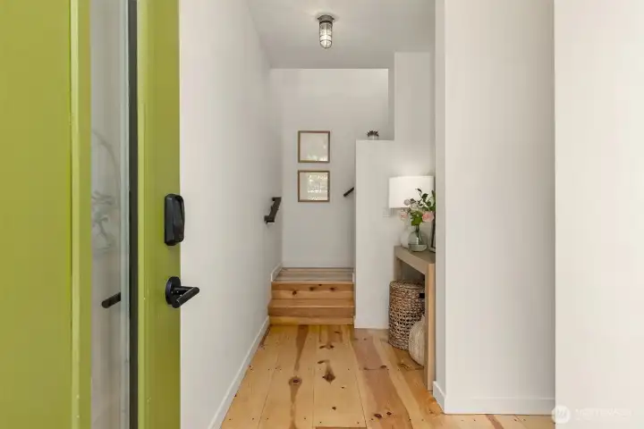 You’re greeted by a sweet entry with wide plank top-nailed pine floors. The bedroom is to the right, and the great room is up the stairs.