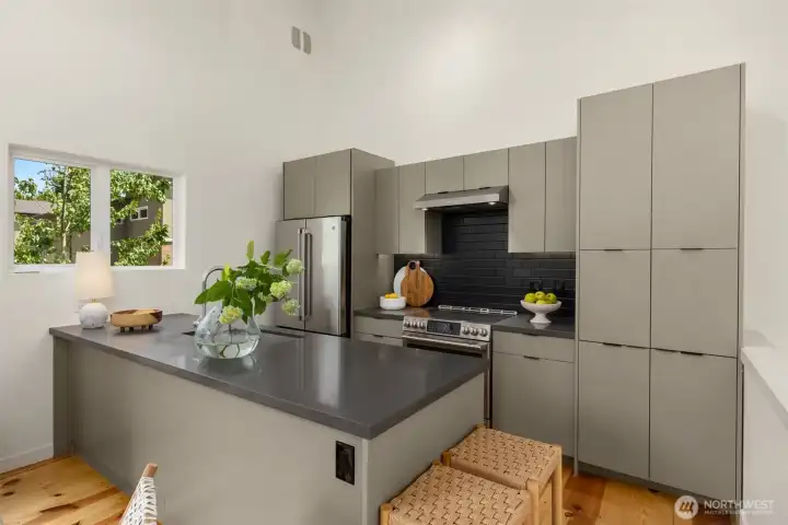 The kitchen offers ample storage and prep space given the petite footprint, and includes quality stainless steel appliances, including an induction cooktop.