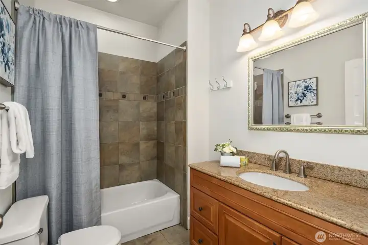 The main-level remodeled full bath with tile floor and tub surround.