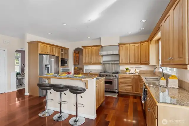This kitchen is all about elevated living! Beautiful hickory cabinets complement the chic granite countertops, while the bar-height breakfast bar on the center island provides the ideal spot for casual dining or enjoying a glass of wine with friends. An arched doorway frames the view of the formal dining room, effortlessly blending casual and formal spaces.