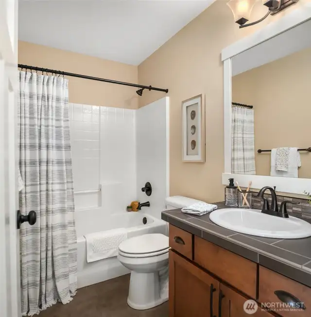 The upper full guest bath offers handsome fixtures and convenient storage.