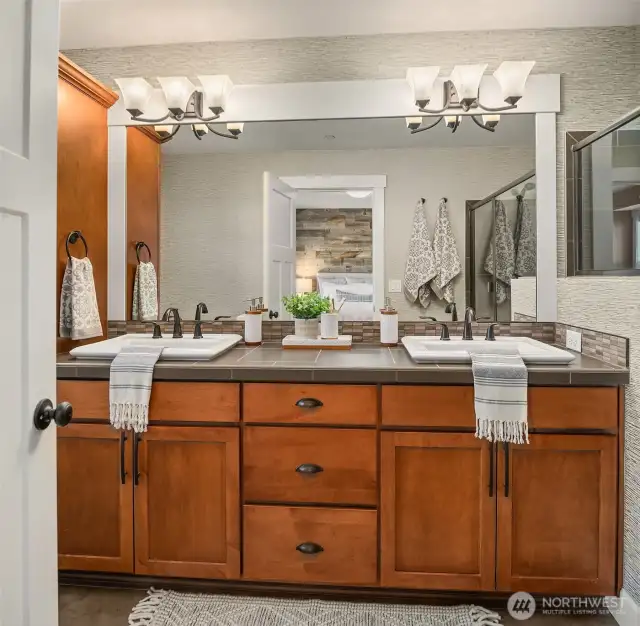 The immaculate primary ensuite bathroom is highlighted by the attractive warm cabinets and oversized mirror.