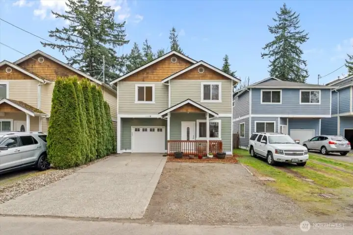 Front exterior of the home with two-story design, gabled rooflines, and a mix of siding finishes. Driveway parking and an attached single-car garage provide convenient access.